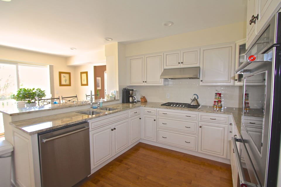 Chefs kitchen with bar seating. Sliding glass doors open to grassy yard & pool.