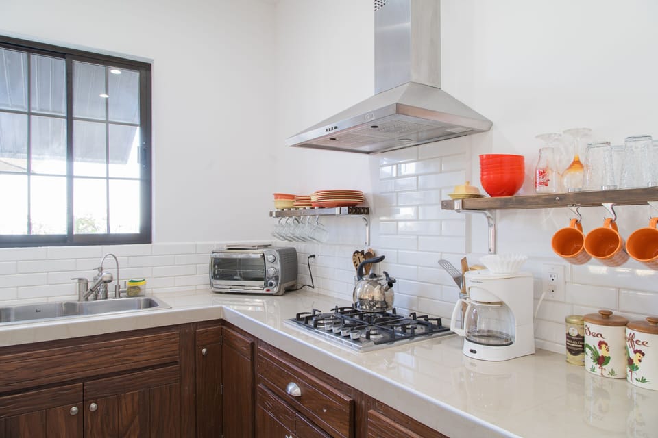 Kitchen with stove, coffee maker, Tea pot, blender, dishes, glassware, etc.