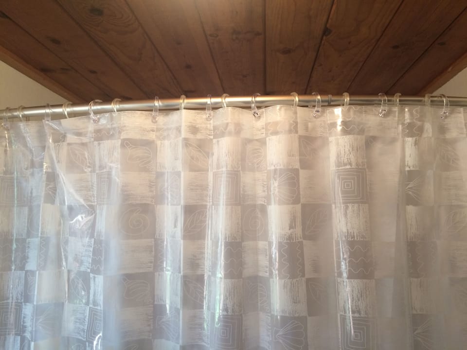 Curved shower curtain over downstairs bathtub.