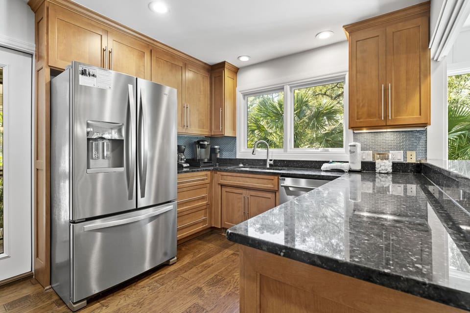 Full equipped kitchen with stove, microwave, dishwasher, fridge, bar seating for 4 and a door leading out to the screened in porch