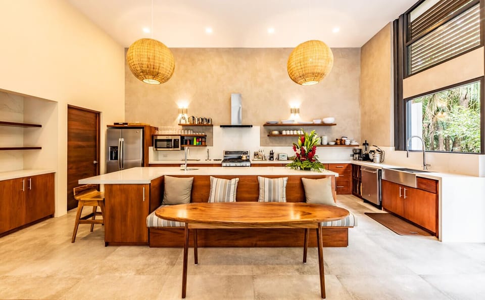 Designer kitchen surrounded by glass, soaring ceiling and a jungle and pool view