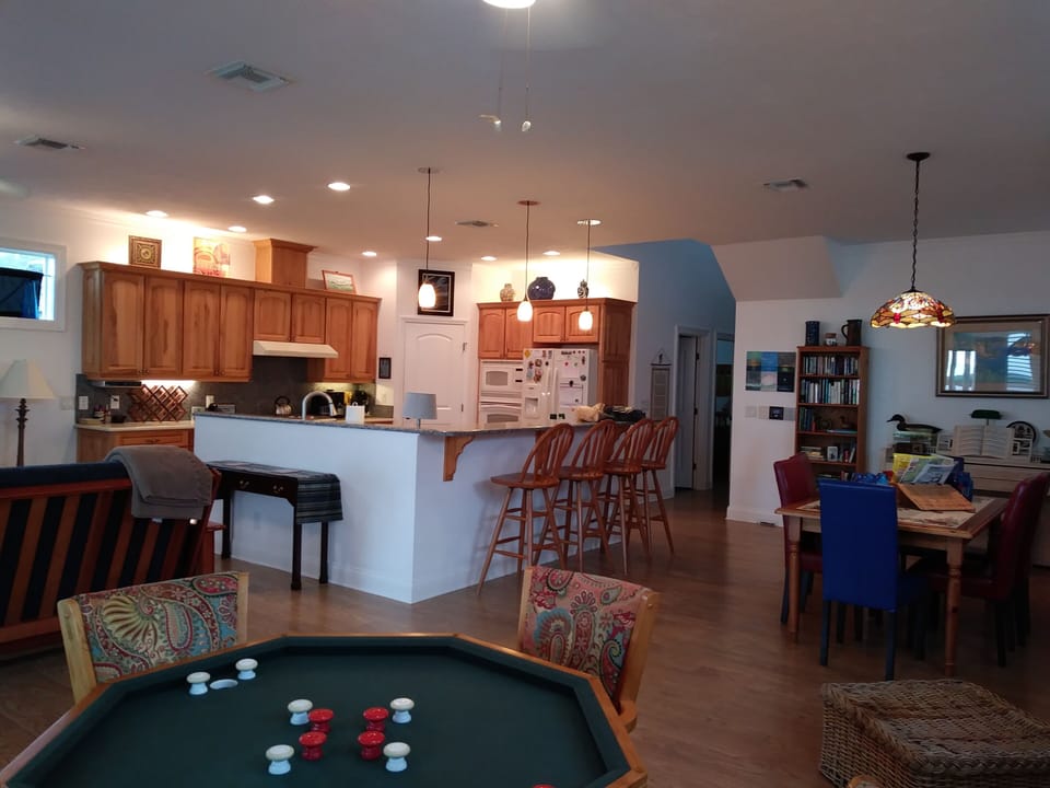 Great room with bumper pool, dining, living room and kitchen overlooking water.