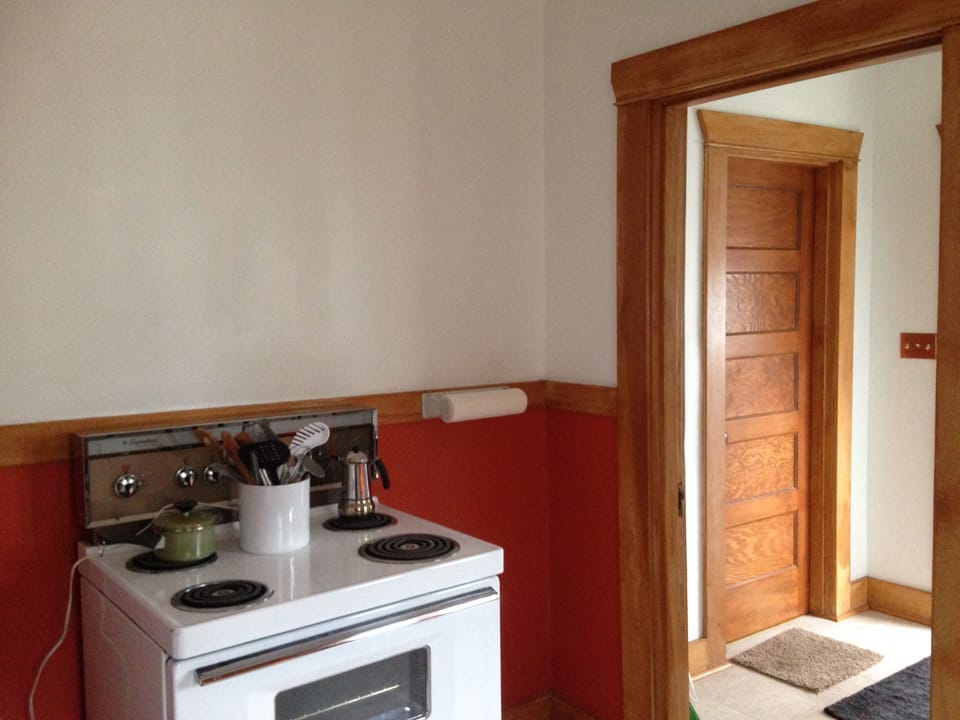 Stove across from sink, doorway to coat hall, sunny porch with washer and dryer