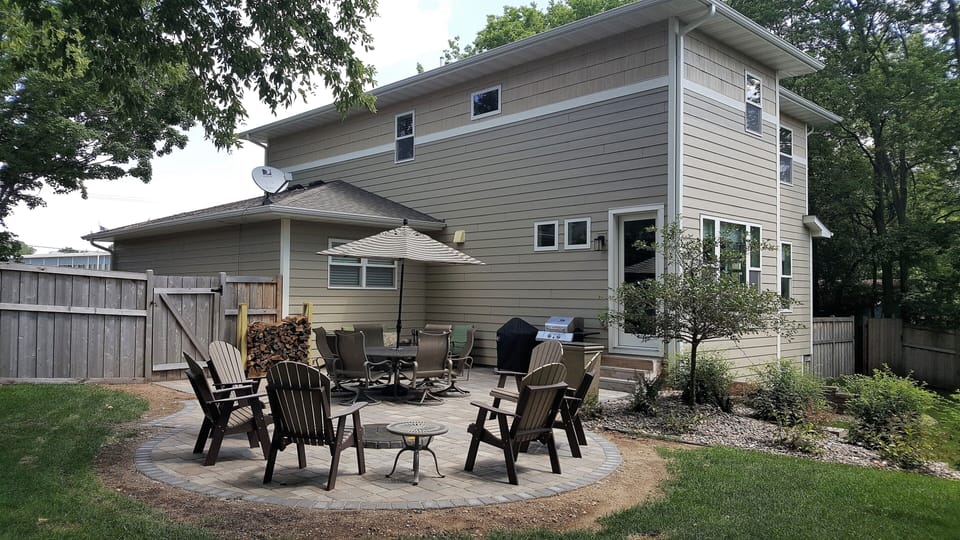 New Paver Patio with Firepit, Dining Table, Couch and Weber charcoal grill.