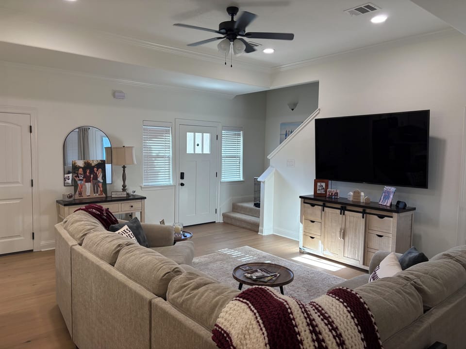 View of living room and entry from hallway with 75” Smart TV
