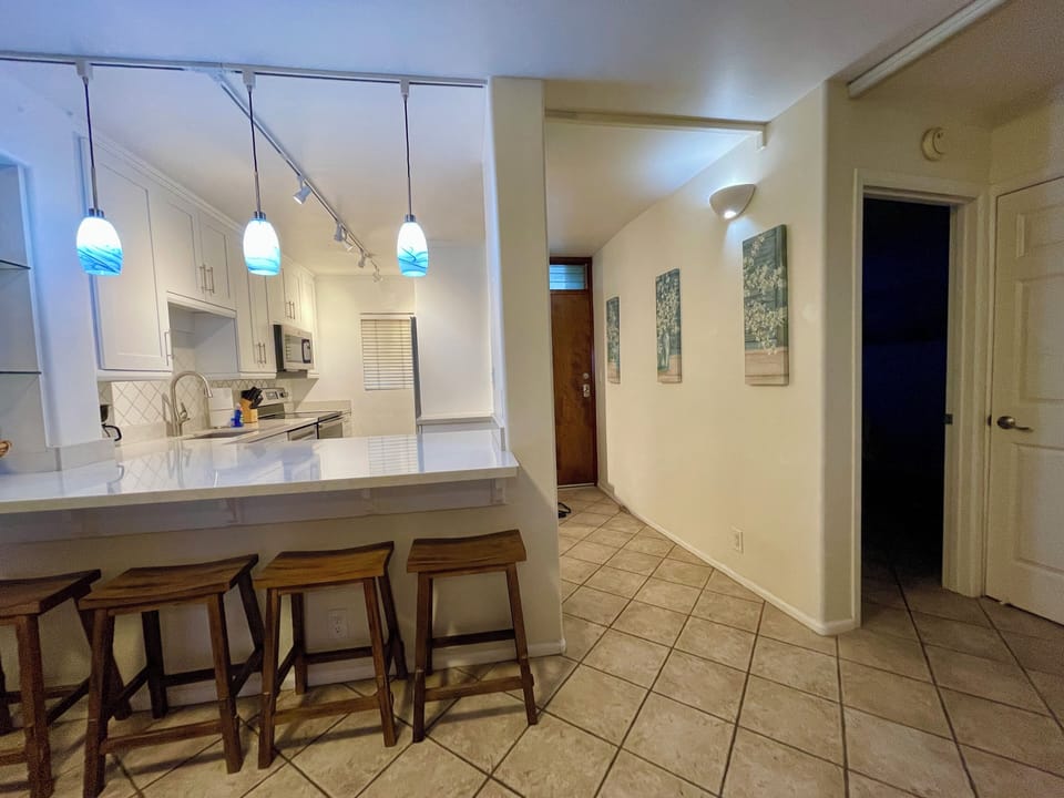 Kitchen quartz countertop bar with entryway and bedroom hallways.