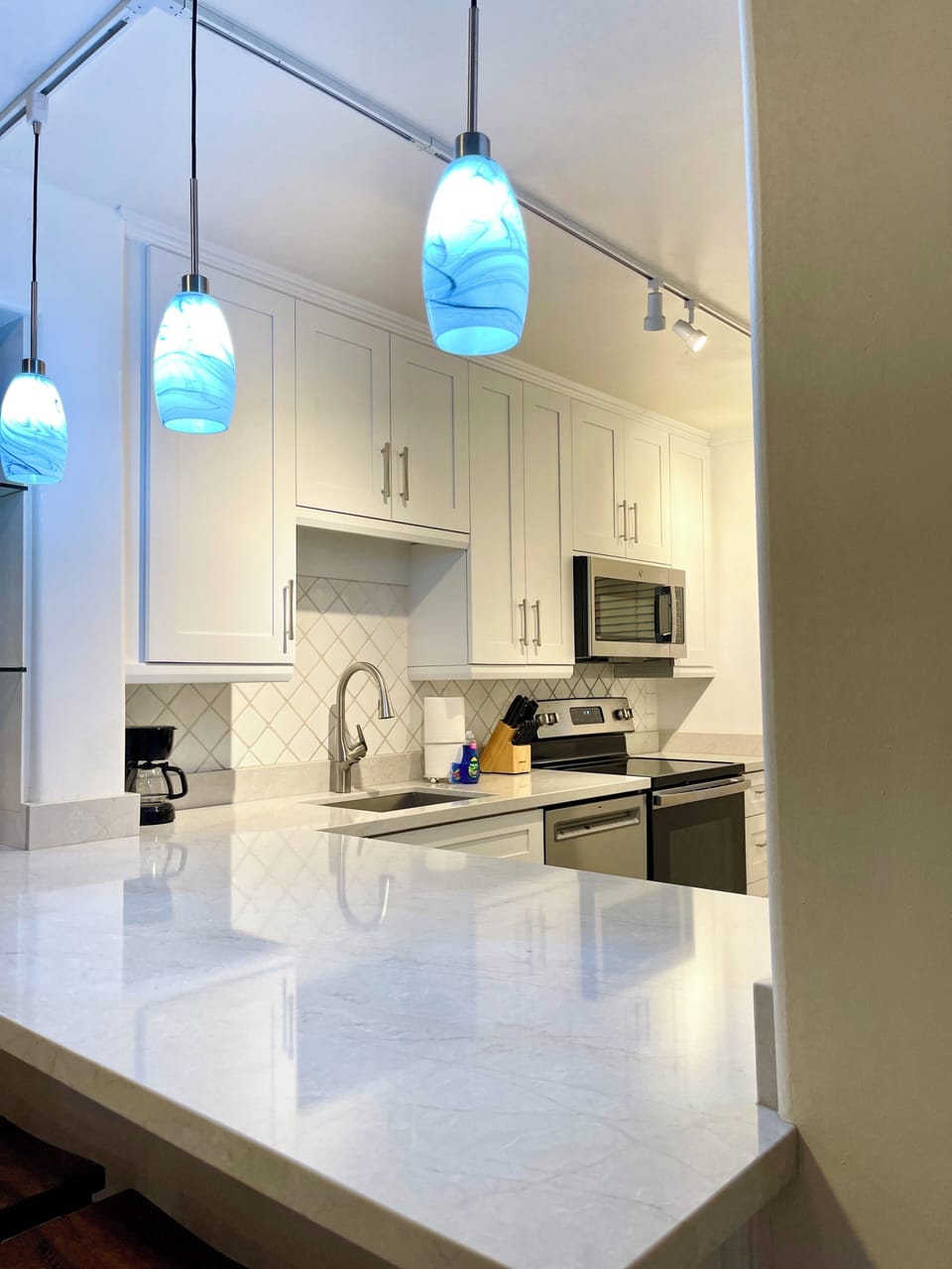 Ocean-view quartz kitchen bar with designer lighting.