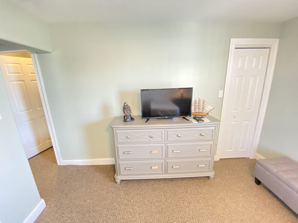 Full size dresser and flat screen television and also an ottoman to store things