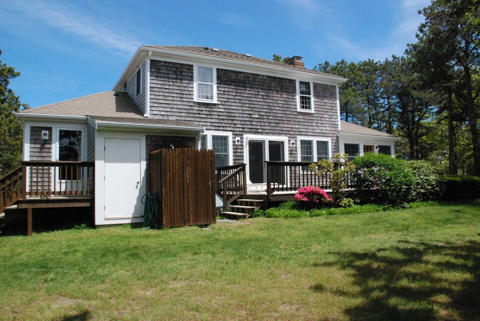 Rear of house showing deck, outdoor shower,  enclosed porch (R).