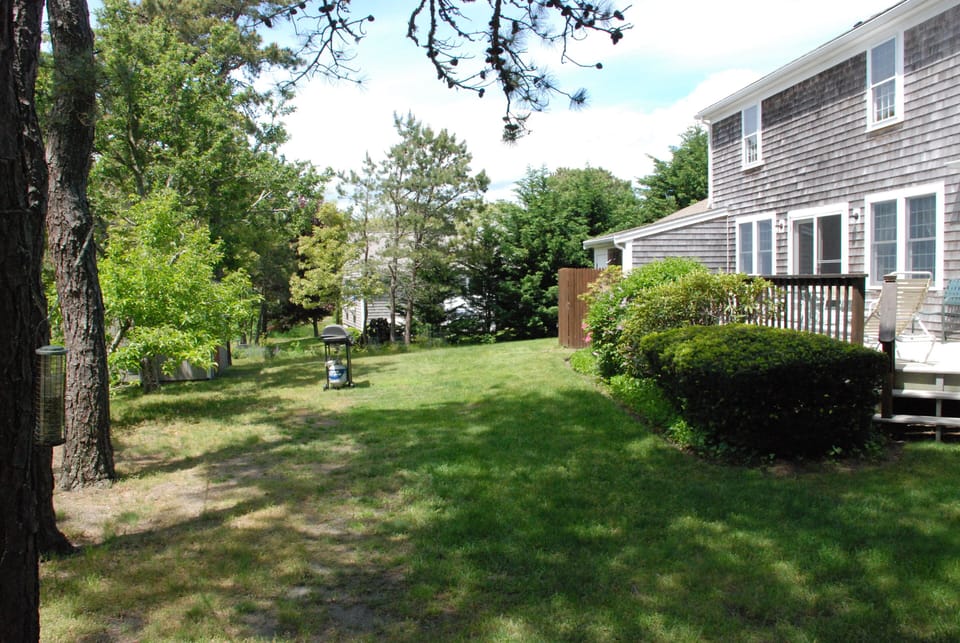 Back yard showing deck (R) , outdoor shower, gas grill. 