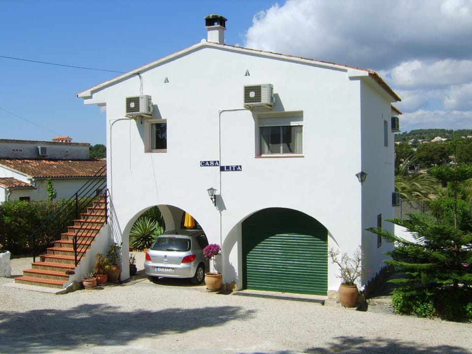 View from entrance gate showing shaded parking, garage and stairs to first floor