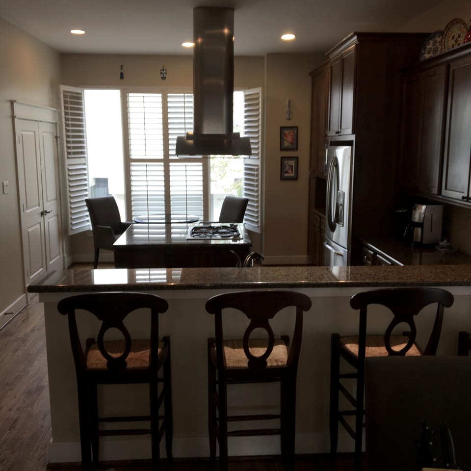 Modern hood, gas range and stove, stainless appliances, island and dining area