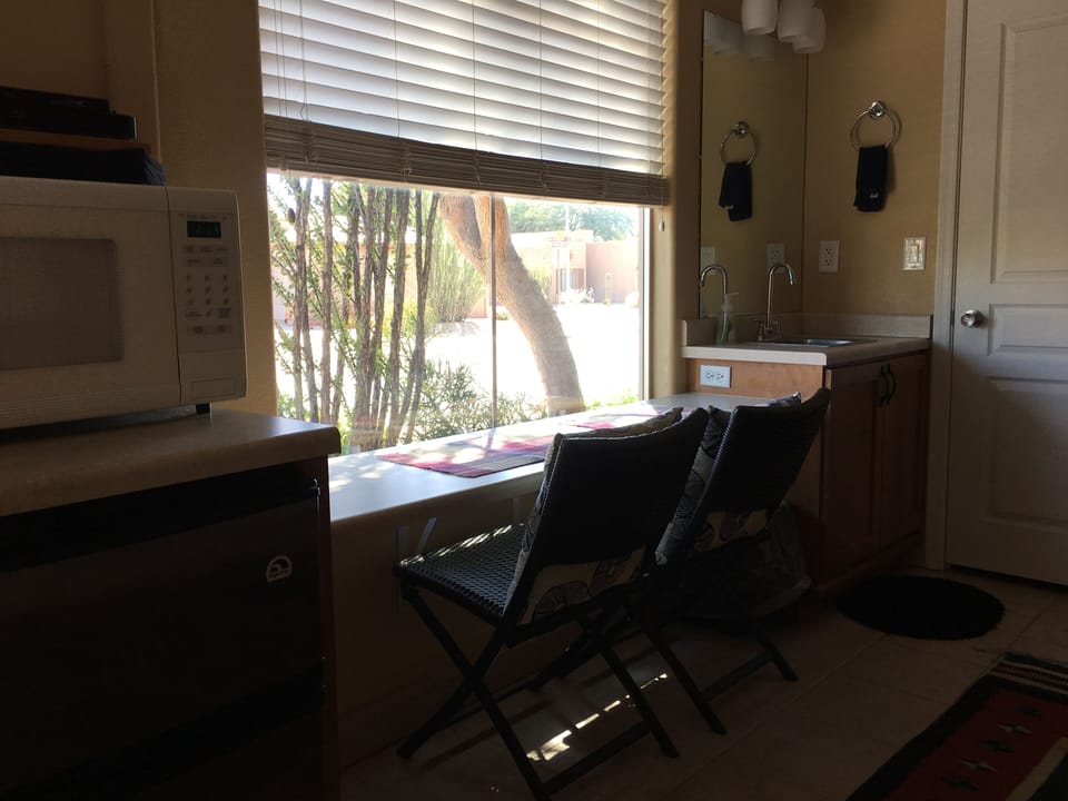 counter with 2 chairs between kitchenette and sink

