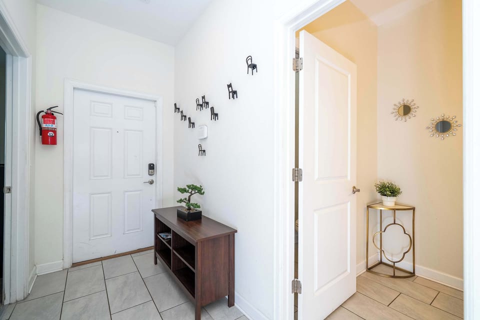 Chic and welcoming entryway! Modern wall art, a touch of greenery, and a peek into a beautifully decorated powder room set the tone for your stay.