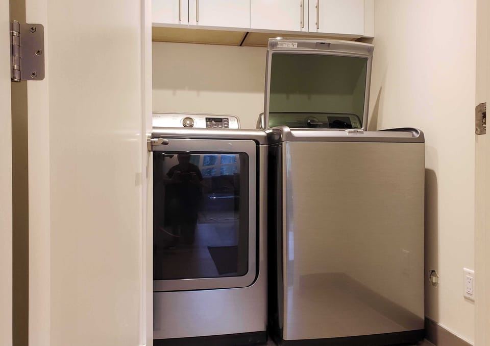 The sound insulated laundry room has a full sized washing machine and dryer.