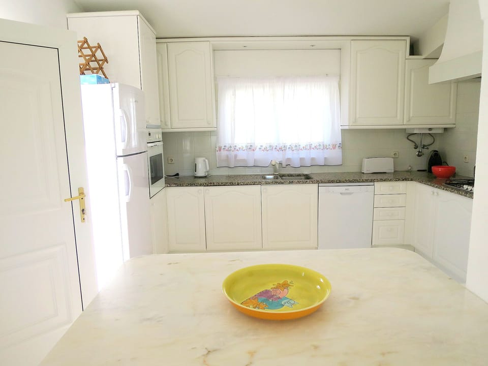 Wide breakfast bar in Kitchen and door to the side patio with table & chairs