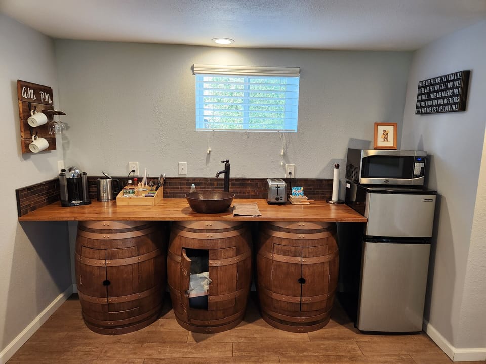 Kitchenette wet bar with fridge, microwave, hot water kettle, and Nespresso.