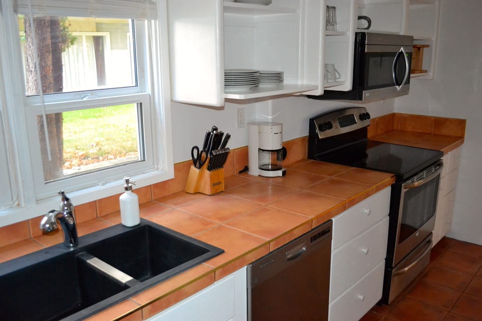 Kitchen stocked with coffee maker, blender, toaster oven, pots and pans, etc
