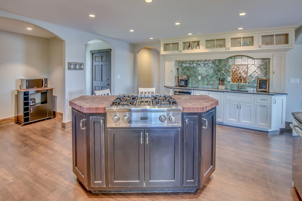 The island of the kitchen, with stove top range and microwave in shot.