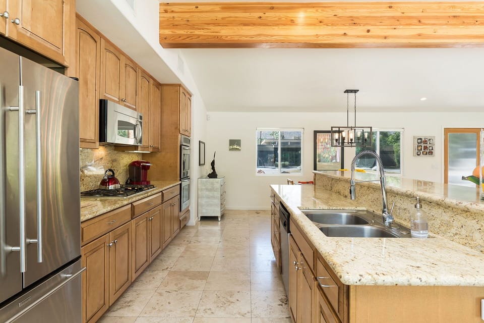 Stainless steel sinks, dishwasher, stove, oven, stainless steel microwave, refrigerator-freezer.  Pool views