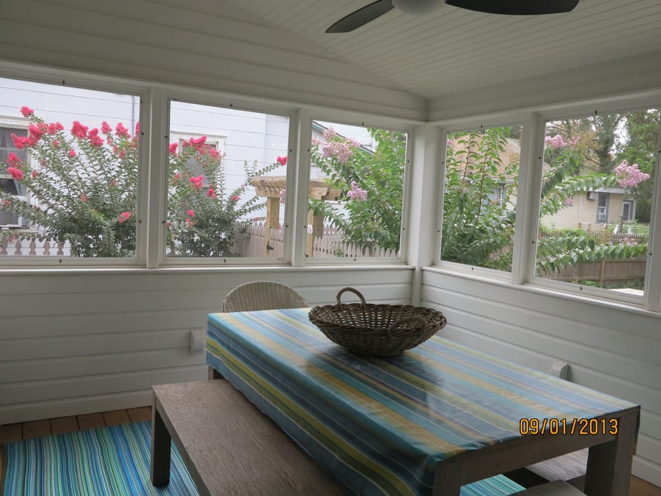 Screened in porch with dining table and flat screen tv on wall