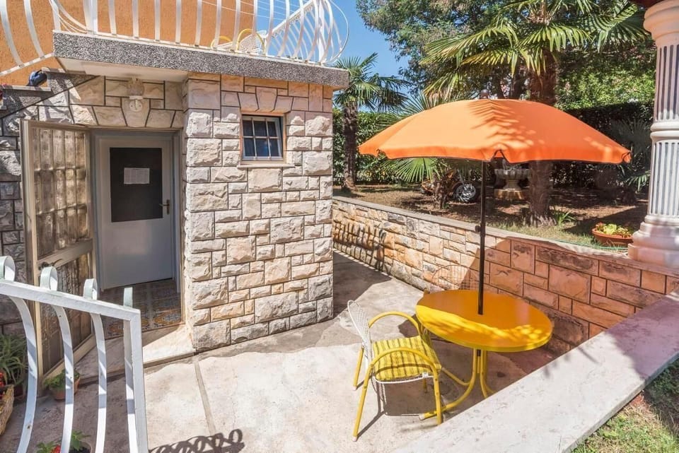 The small terrace with a table and two chairs, umbrella and the entrance to the studio flat
