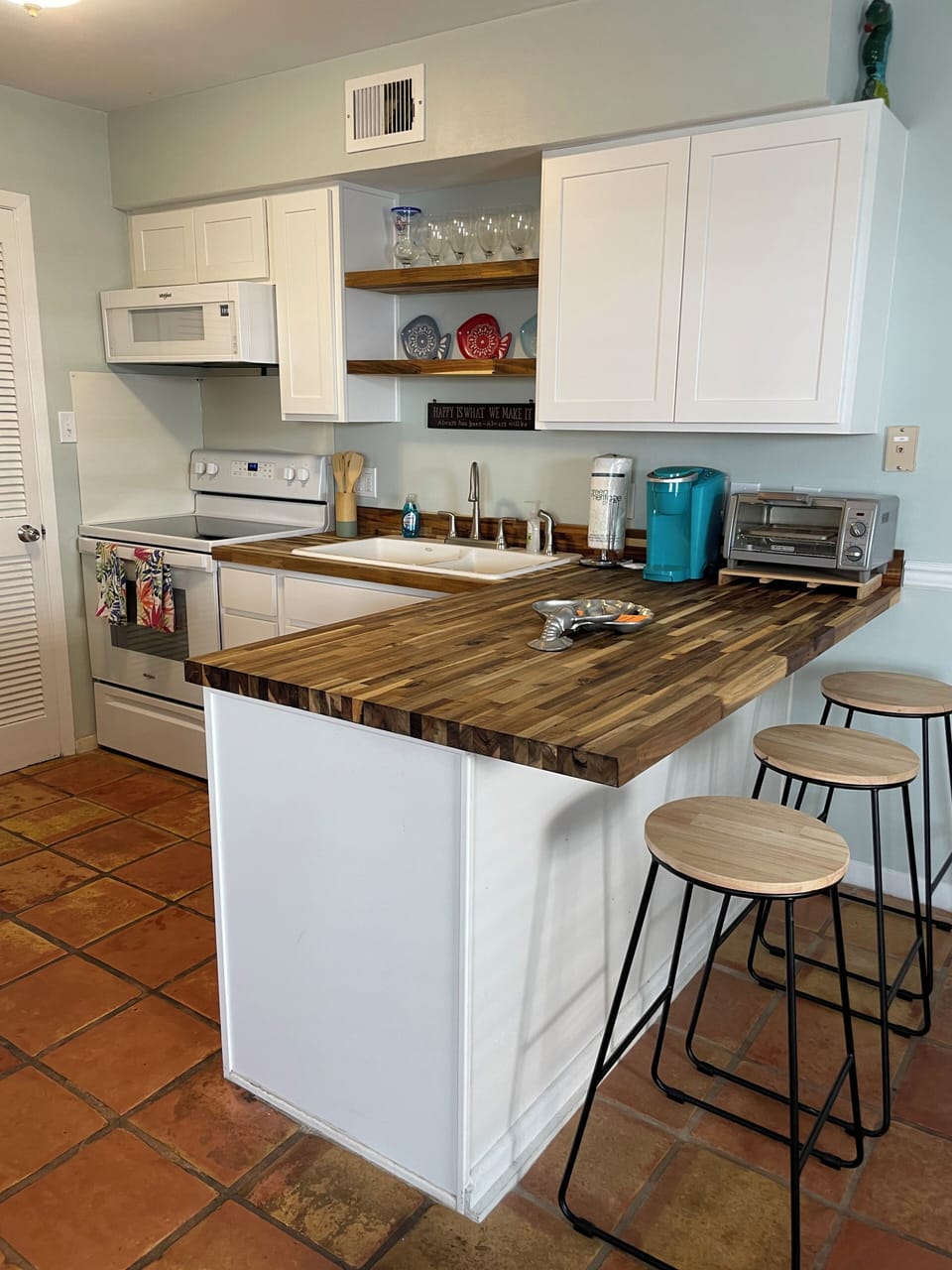 Kitchen includes pots, pans, utensils and bar stools.