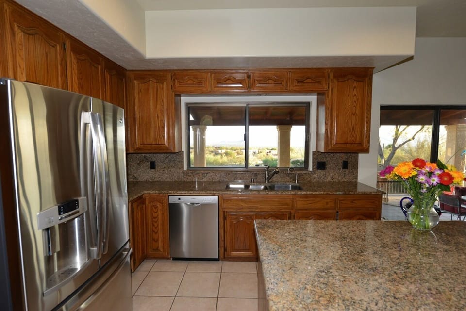 Kitchen has new stainless appliances and a view of city and kitchenette table.