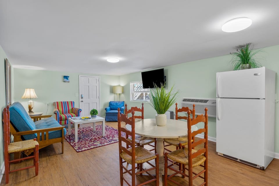 Your bright open-plan space combines living and dining seamlessly, with colorful seating, a flat-screen TV, and full-size fridge for comfortable self-catering stays.
