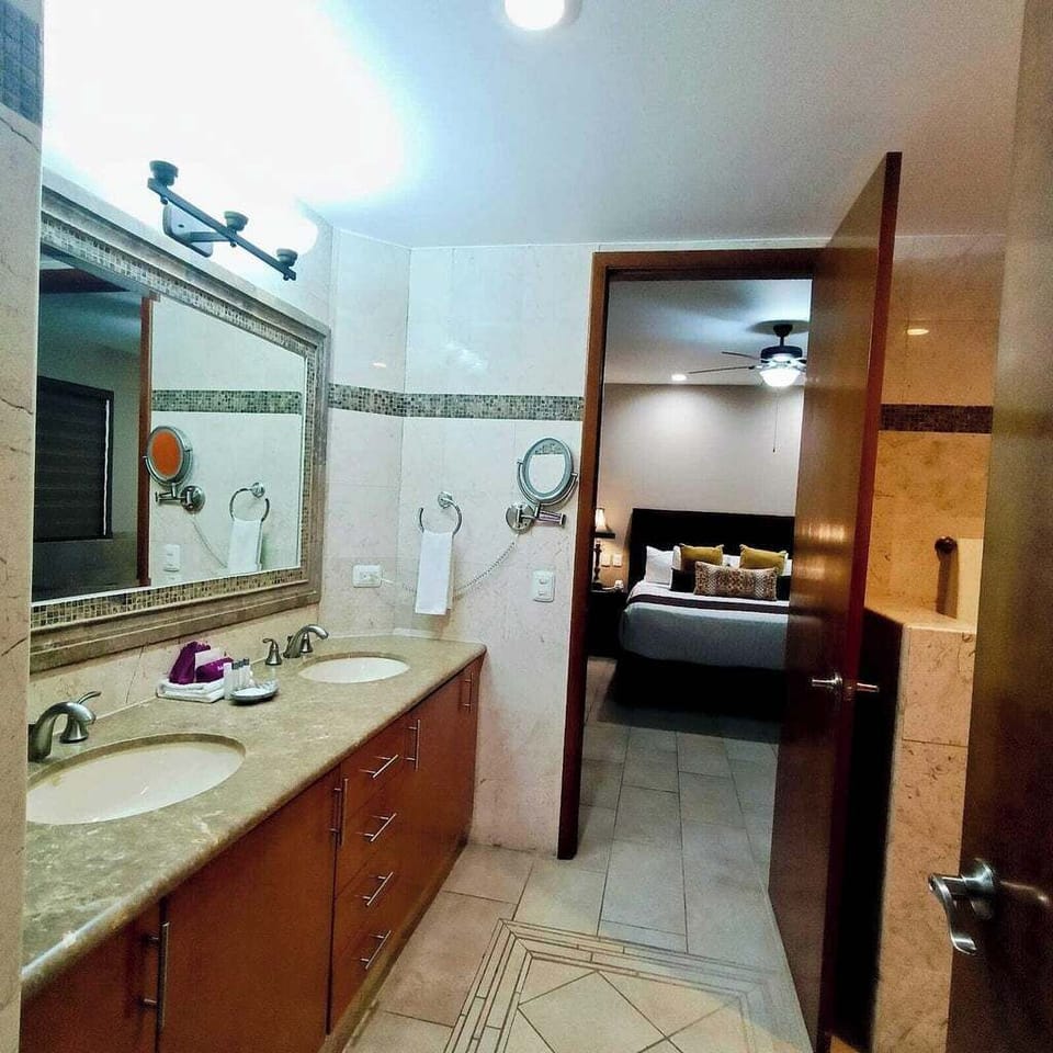 Bathroom with shower, double sink vanity, hair dryer, magnification mirror.