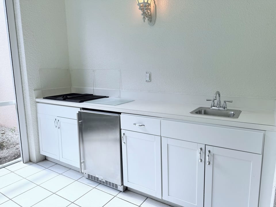 Full outdoor kitchen on lanai with refrigerator.
