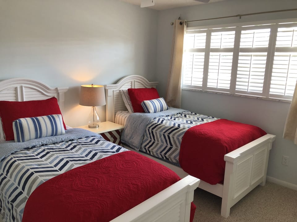 Guest bedroom with two twin beds, closet, nightstands, and plantation shutters