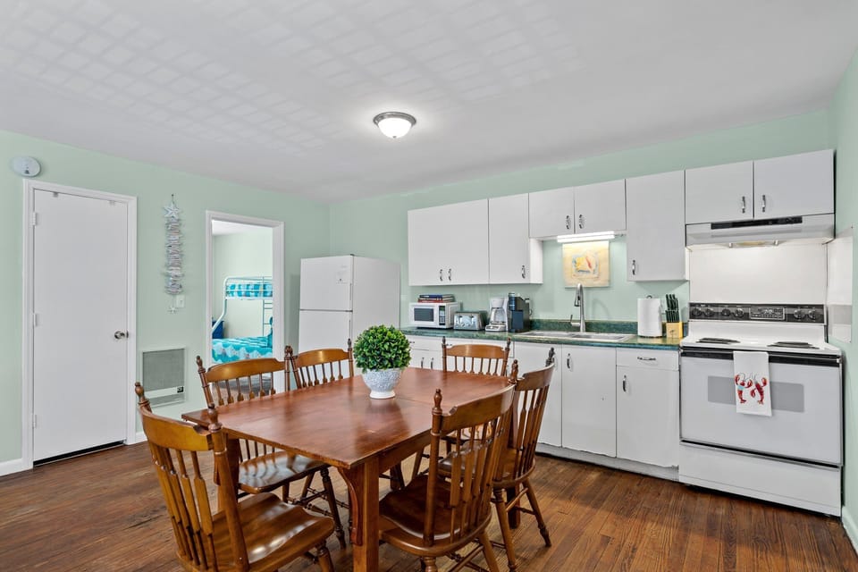 Your spacious kitchen invites memorable meals with its warm wood dining table, modern appliances, and cheerful mint walls creating the perfect gathering space.