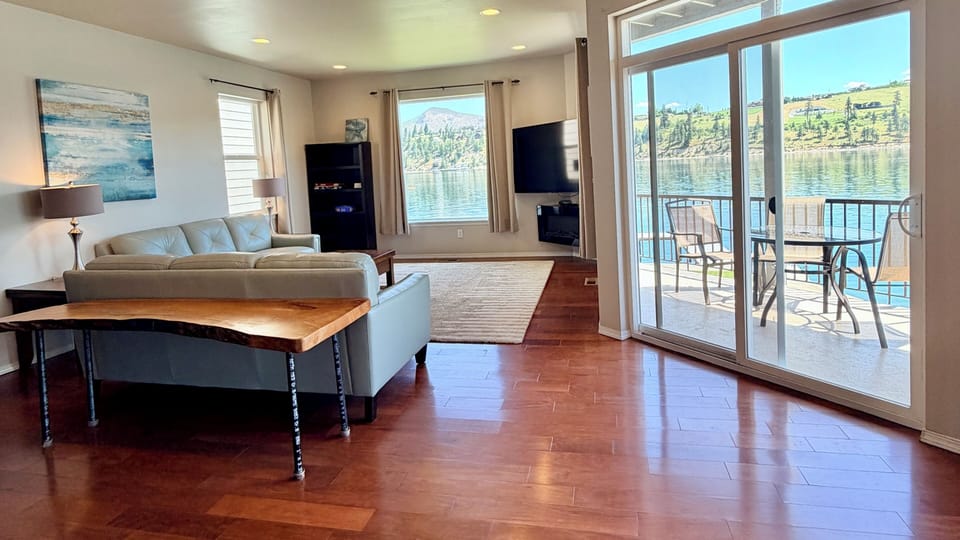 Large open living room with a 60" flat-screen TV and big views along with a covered deck area looking out over beautiful Lake Chelan