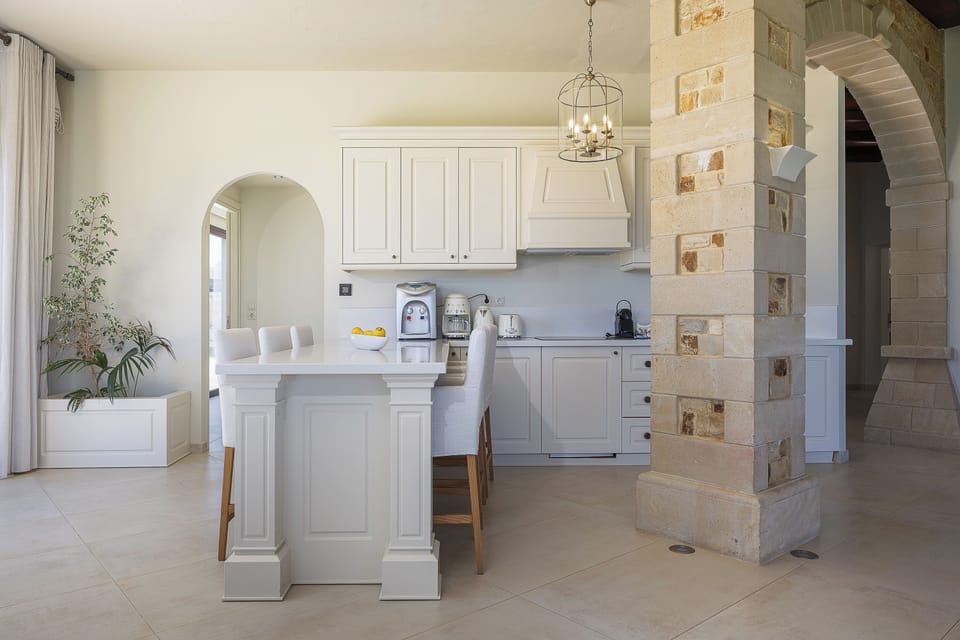 Kitchenette area with mini fridge, stove, Nespresso machine, electric kettle, sink, and bar with two stools