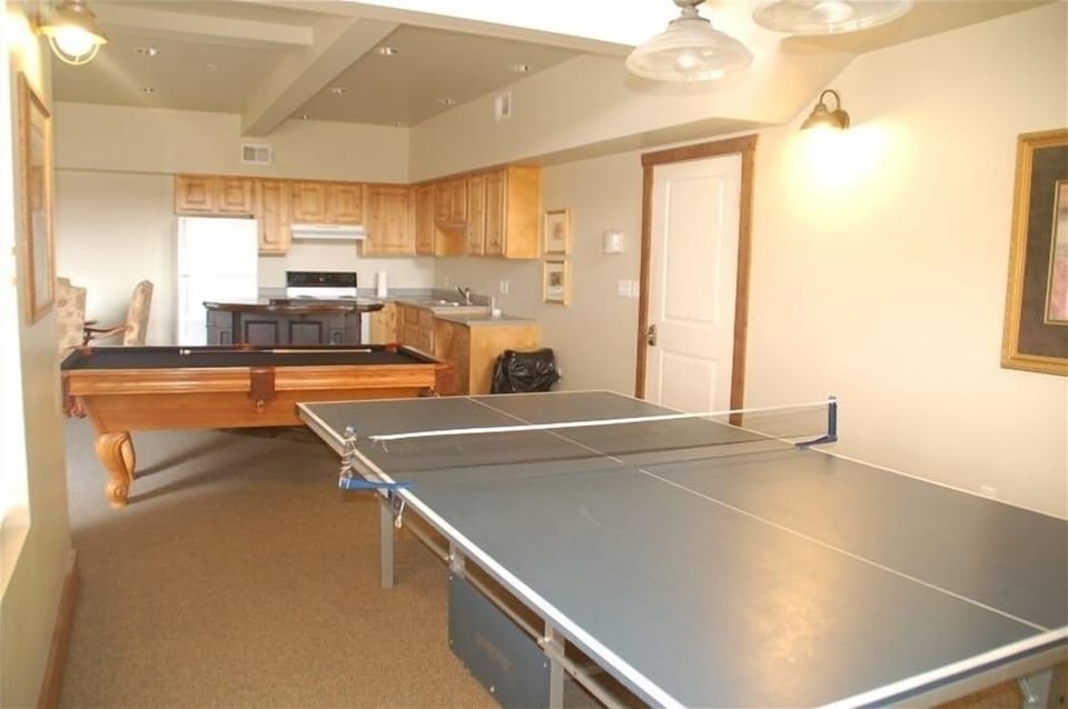 Community center with ping pong table, pool table, kitchen and seating with tv.