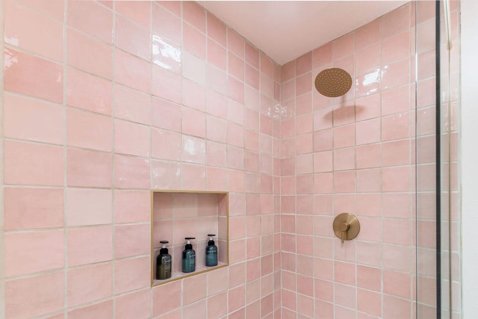 Rain shower surrounded by pink Italian tiles.