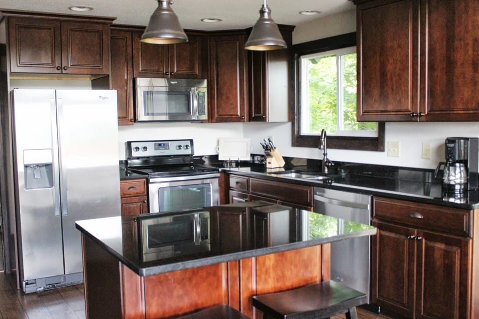Open concept kitchen includes island bar, overlooking dining & living area