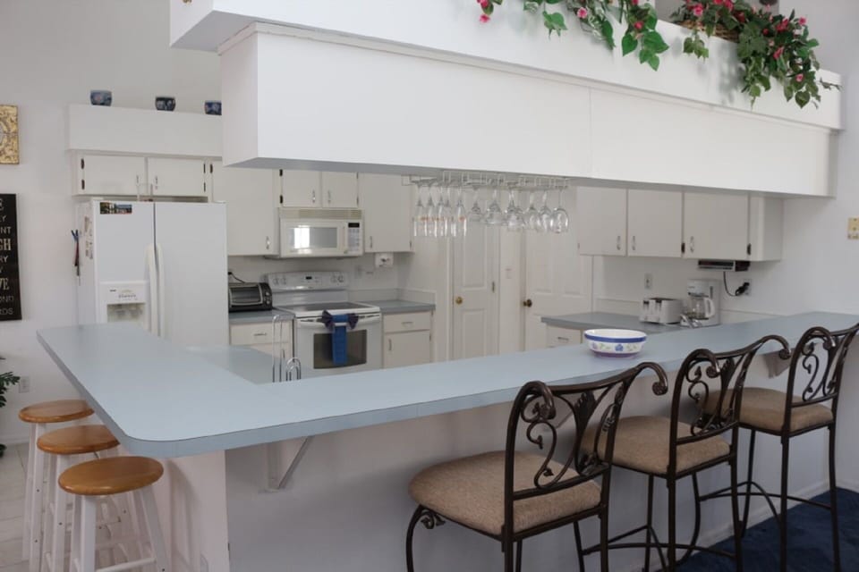 Huge kitchen with L-shaped counter/bar overlooking open concept living room