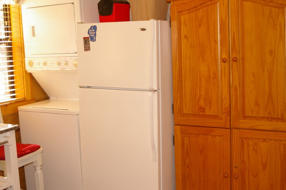 Stack washer and dryer next to full size refrigerator, adjacent to an amour