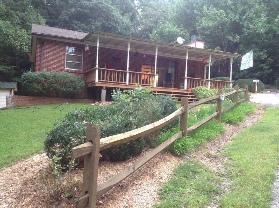 The split rail fence and side porch welcomes all to the Cozy Cabin.