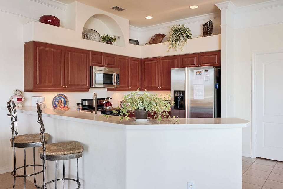 Breakfast bar with seating, stainless appliances, and warm wood cabinetry.