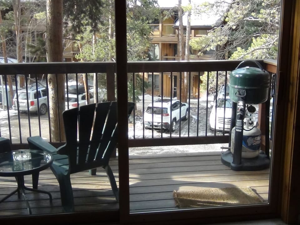 Deck off the living room with 2 chairs and a gas grill