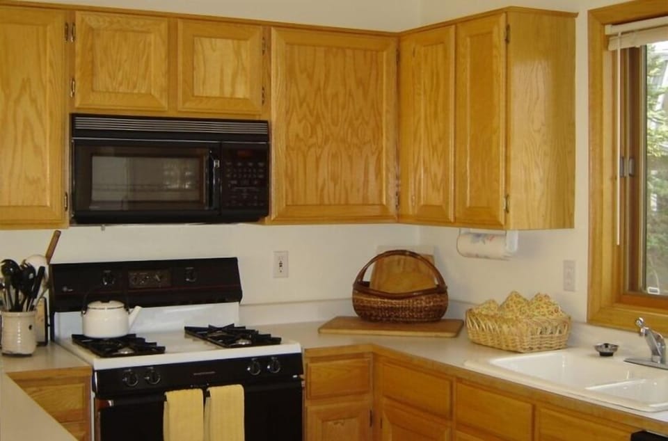 Kitchen has a bar counter on left side that separates kitchen and dining room.
