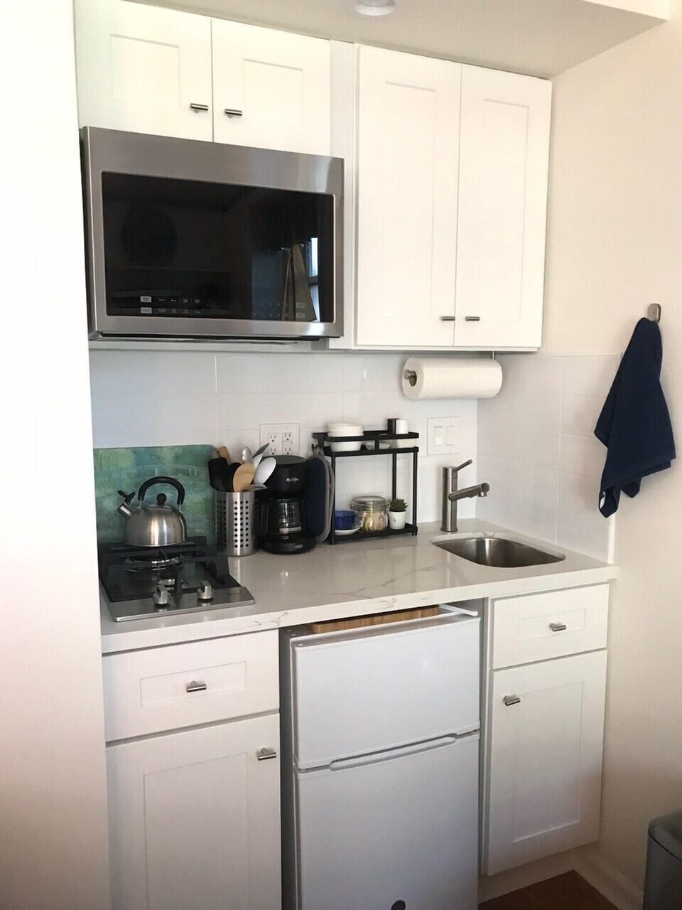 Mini kitchen with gas stove top, microwave/ convection oven, fridge, sink .