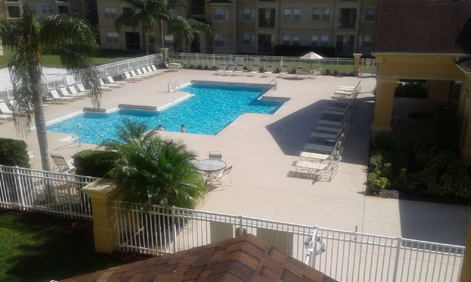 Beautiful, sparkling pool with loungers, shaded tables and clubhouse/hot tub.