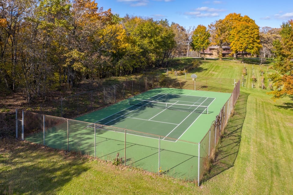 Tennis court with lake house in the background.