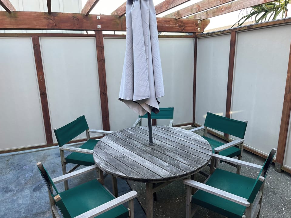 Outdoor dining table in private patio with Weber Q barbecue and 2 sunloungers 