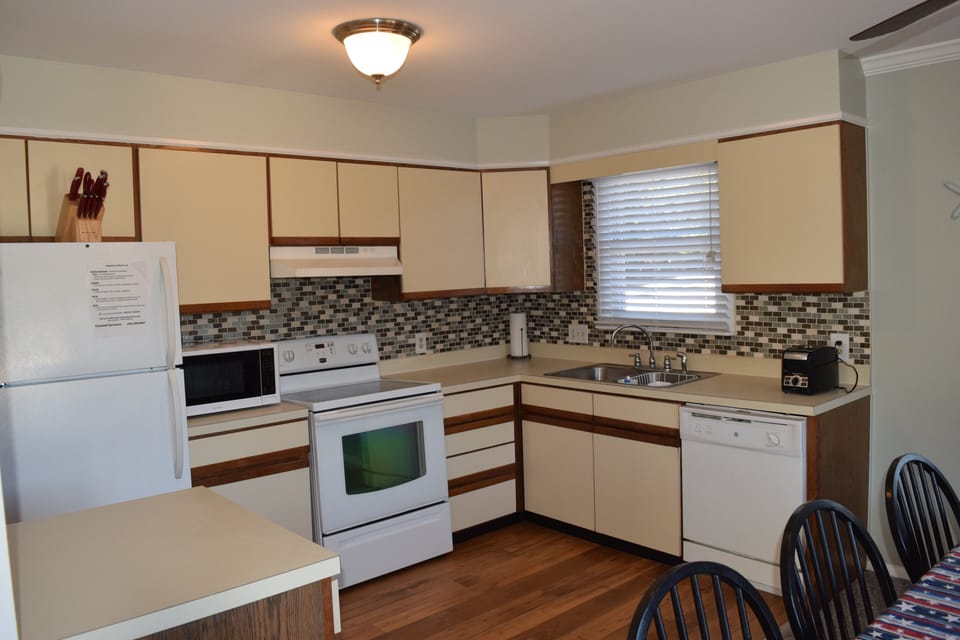 Kitchen w/ refrigerator, microwave, stove, coffee maker, toaster, crock pot.