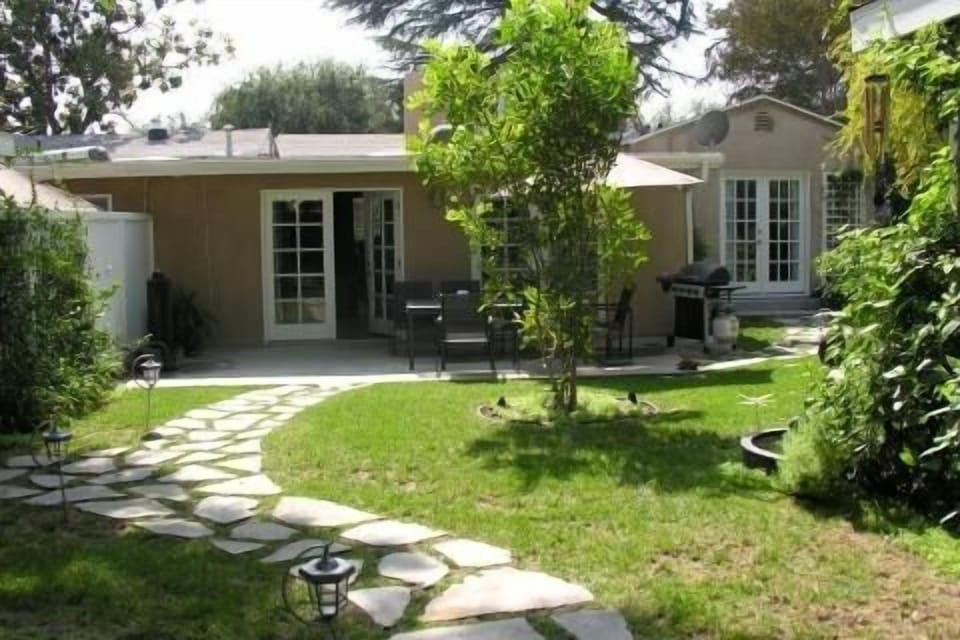 Rear garden view towards back patio with gas grill and seating for 6
